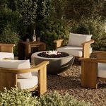Outdoor fire table lit and styled in garden seating area with wooden chairs and gravel ground