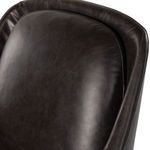 Close-up on padded upper backrest of chair in smooth black leather