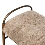 Top corner close-up of the cream shearling cushion and curved brushed iron arm