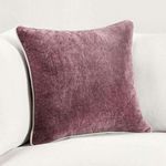 Pillow styled upright on a white couch against a plain wall, showing scale