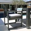 Redondo Dining Chair placed next to outdoor patio table with pool and modern house in background