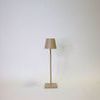 Vera Sand Poldina Pro Table Lamp with a tall, slim sand-colored metal base and matching tapered lampshade