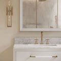 Close-up of Verona vanity marble countertop and gold faucet with matching gold wall sconce and mirror trim