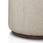 Close-up of ottoman's fabric texture and stitching above dark wooden base