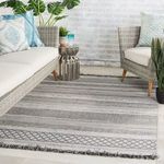Indoor living room with gray rug, wicker furniture, metal side table, and blue decorative pillows
