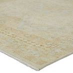 Close-up of rug corner showing short fringe and detail-rich border with pastel colors and worn texture