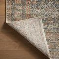 Backside of rug folded to show tightly woven backing with muted color pattern
