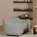 Bria sofa in living room setting with shelves, books, and decorative vase in warm beige tones
