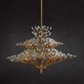 Lit chandelier viewed from bottom, emphasizing tiered gold branch layers and glowing bulbs