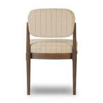 Back view reveals chair’s curved cushioned upholstery framed by vertical brown oak supports