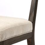 Detailed view of seat cushion's upholstery meeting wood frame beneath backrest