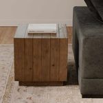 Jasper accent table next to gray couch on patterned rug with a book on top in a styled living room setup.