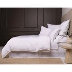 Bed made with Blake White/Ocean Duvet in room with dark wall paneling and natural wood side table