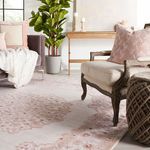 Angle view of Malo Medallion rug under wood armchair with pink pillow and brown knitted ottoman