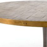 Angled close-up of table edge showing polished brass steel band with a warm patina and single screw
