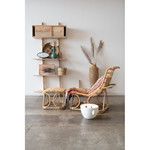 Bowl placed on concrete floor beside rattan chair and shelving with natural home accessories