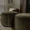 Side view of two velvet ottomans on patterned rug in warm, neutral-toned room
