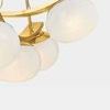 Close-up of two textured seedy glass shades and curved brass metal elements of Duxbury Chandelier