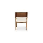 Back view focusing on carved detail of tan leather backrest and oak frame edges