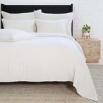 Bed styled with multiple Vancouver Shams and matching cream bedding arranged on a natural fiber rug