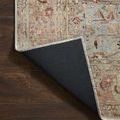 Corner of Adrian Ocean Clay rug flipped to reveal solid black non-slip backing and stitched edge