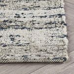 Side angle highlighting woven wool edge and low pile thickness against wooden floor