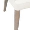 Close-up of Aurora Dining Chair’s natural gray wooden leg and white leather upholstery stitching detail