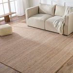 Rosier rug styled in living room with beige sofa, pouf, and natural light on wood floor