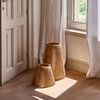 Two natural jute lanterns placed on wood floor near window and white curtain in bright room