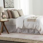 angled bedroom view showing pink and white runner rug under bed with neutral throw pillows and decor