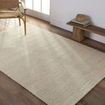 Rug styled in a room with wood flooring, natural light, mid-century chair, and bench