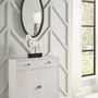 Oval mirror showing lamp reflection, hanging over white cabinet with horse sculpture near window with sheer curtains