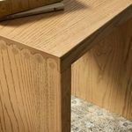 Close-up of end table top with books and mug, focusing on wood grain and scallop edge detail