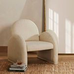 Nicola chair placed in a room on a textured rug with sunlight casting window shadows
