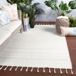 Rug styled in outdoor patio setting with sofa, plants, and pillows on wood flooring
