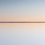 Soft gradient sky and water reflection with balanced warm peach and cool blue hues