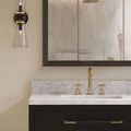 Byford Bath Wall Sconce shown on left wall above marble countertop with gold faucet and shower visible in mirror