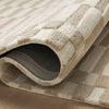 Bradley Ivory Beige Rug partially rolled over revealing dark grey backing fabric