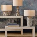 Weststrand Table Lamp on left side of a layered white stone console table in styled room with other lamps and textured blu...