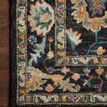 Close-up of rug corner showing dense wool texture and detailed multicolor floral pattern on dark background