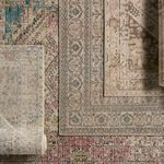 Stacked and overlapping rectangular rugs in a variety of traditional motifs and faded color palettes including gold and ivory