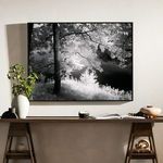 Framed photo above a wooden desk with minimalist decor including books, beads, and vases