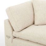Close-up of the sectional’s fabric texture and back cushion with visible piping detail and metal bracket on the arm