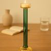 Single lit candle holder placed on wooden table with blurred beige background