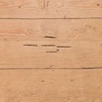 Close-up of tabletop surface displaying natural wood grain patterns and small distress marks