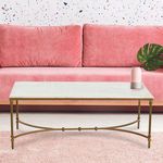 Styled living room setting with marble coffee table in front of a pink sofa on a light pink rug