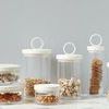 Nine assorted Bianca canisters stacked and filled with various dried foods on marble surface