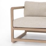 Close-up view of light wood base frame and front corner of beige cushion