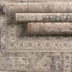 Multiple rolled rugs stacked atop each other showcasing variation in color tones and pattern details