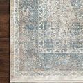 Corner view of rug laid on dark hardwood floor highlighting intricate border design and soft texture